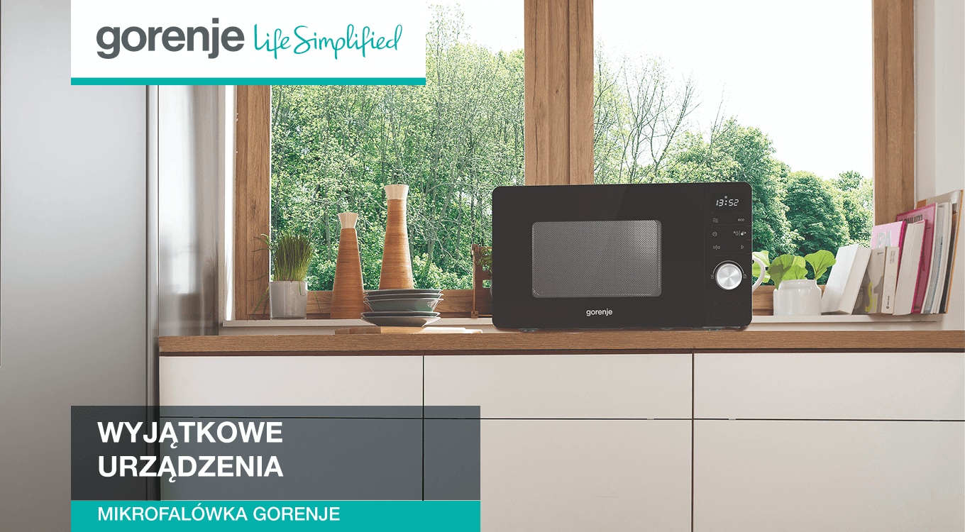 Mikrofalówka Gorenje na kuchennym blacie przy dużym oknie, w jasnej kuchni. W lewym górnym rogu widoczne logo Gorenje z hasłem „Life Simplified”.