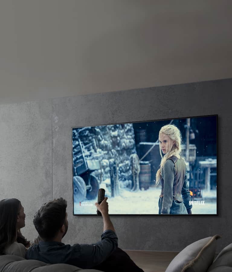Obraz przedstawiający parę oglądającą program telewizyjny na telewizorze LG UHD.