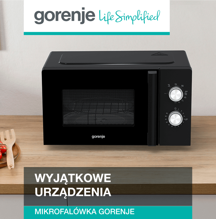 Czarna kuchenka mikrofalowa marki Gorenje stojąca na drewnianym blacie kuchennym. Obok znajdują się warzywa na desce do krojenia oraz ceramiczny dzbanek. W lewym górnym rogu widoczne logo Gorenje z hasłem „Life Simplified”.