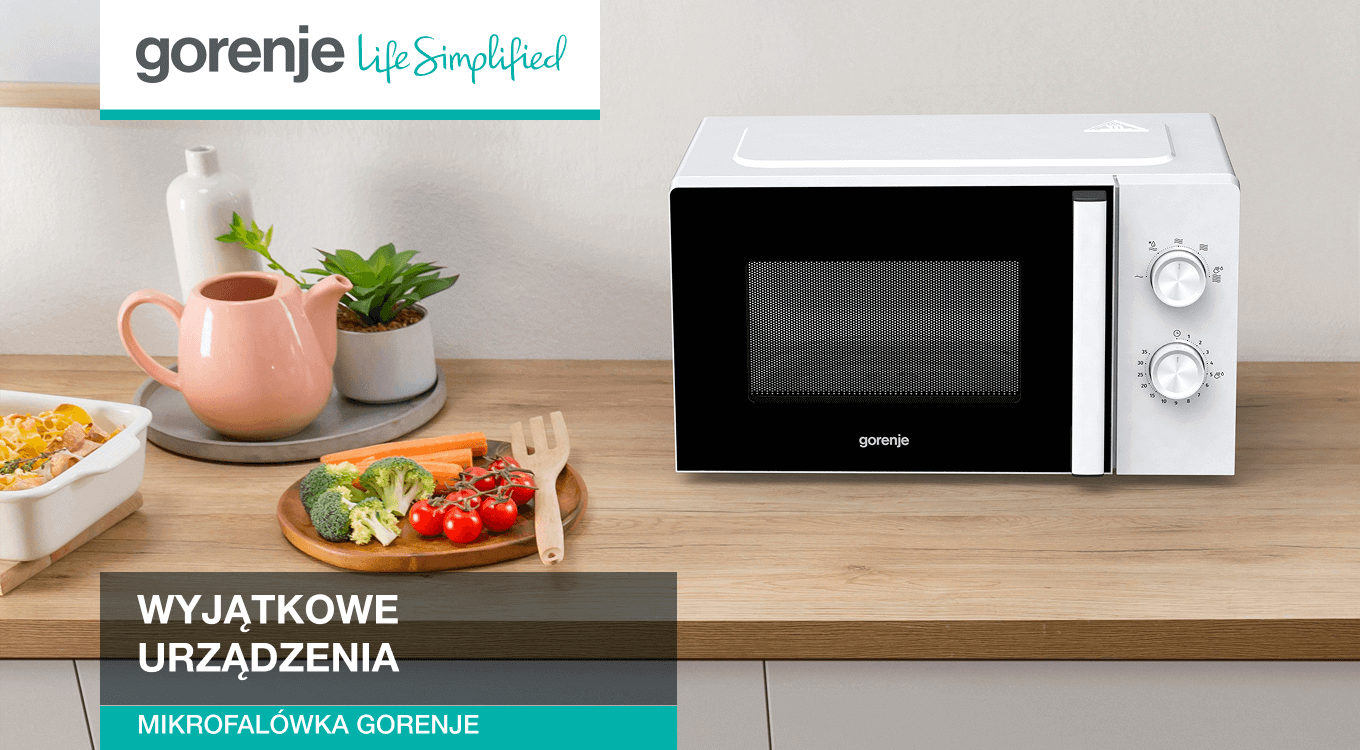 Biała kuchenka mikrofalowa marki Gorenje stojąca na drewnianym blacie kuchennym. Obok znajdują się warzywa na desce do krojenia oraz ceramiczny dzbanek. W lewym górnym rogu widoczne logo Gorenje z hasłem „Life Simplified”.