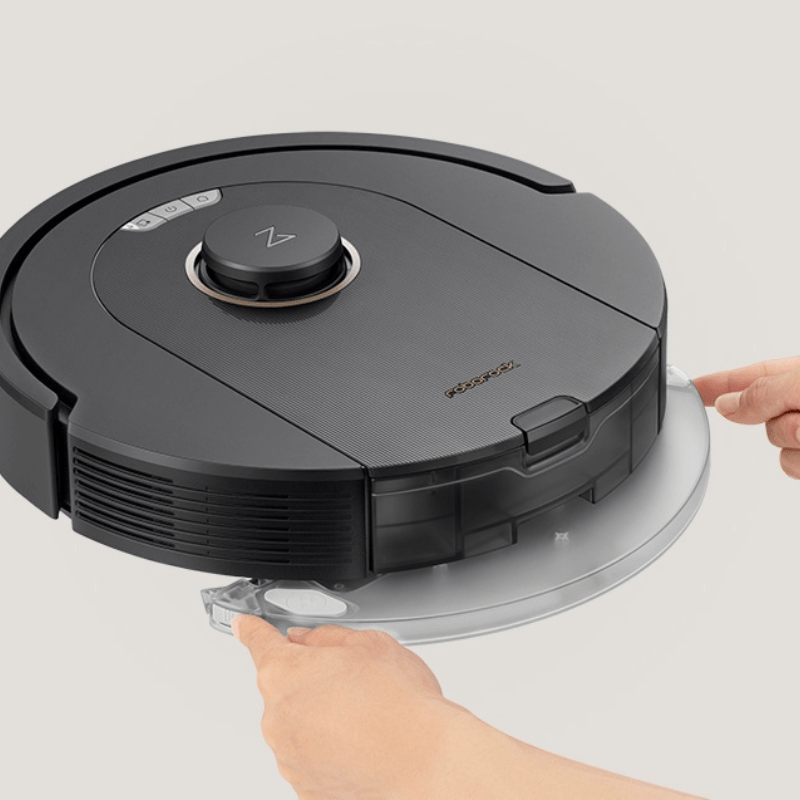 Dłonie demontujące moduł mopujący robota Roborock Q5 Pro na szarym tle