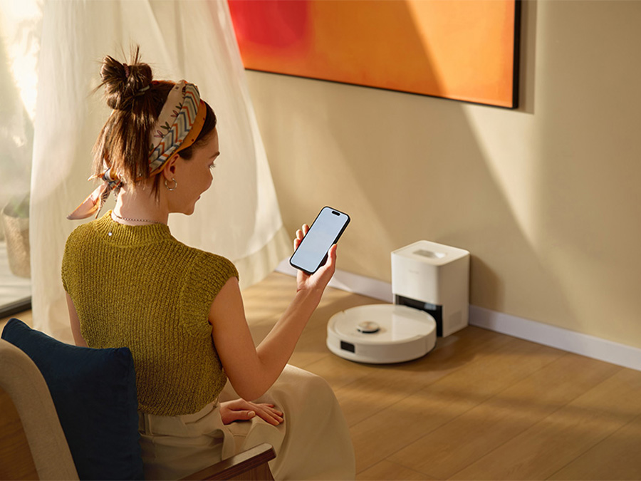 Kobieta obsługująca robota sprzątającego Roborock Q10 VF za pomocą aplikacji na smartfonie