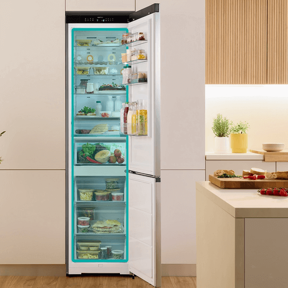 Otwarta lodówka w jasnej obudowie Gorenje wypełniona produktami i z zaznaczoną na niebiesko częścią chłodziarki i zamrażarki