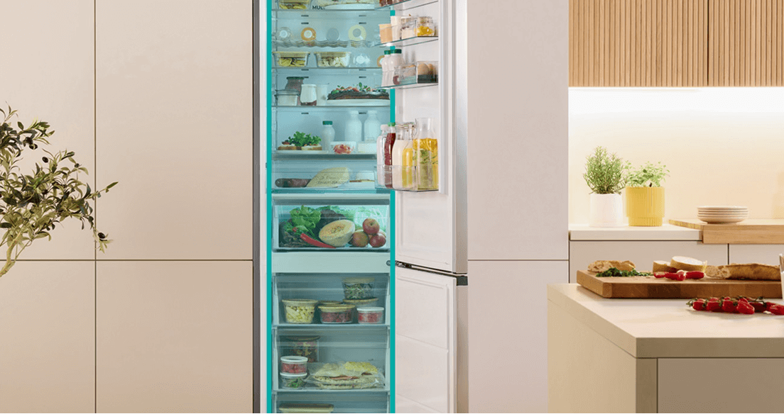 Otwarta lodówka w jasnej obudowie Gorenje wypełniona produktami i z zaznaczoną na niebiesko częścią chłodziarki i zamrażarki