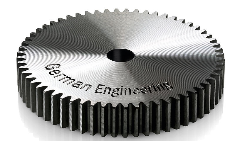 Metalowa zębatka kołowa z wygrawerowaną nazwą German Engineering.