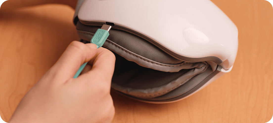Ładowanie złożonego masażera oczu SKG ES500 za pomocą turkusowej wtyczki USB (Universal Serial Bus) typu C
