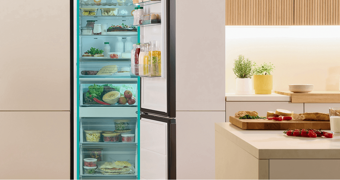 Otwarta lodówka w jasnej obudowie Gorenje wypełniona produktami i z zaznaczoną na niebiesko częścią chłodziarki i zamrażarki