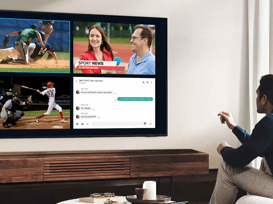 Mężczyzna korzysta z funkcji QLED Multi View, by oglądać mecz piłki nożnej i czytać wiadomości na tym samym ekranie, w tym samym czasie.
