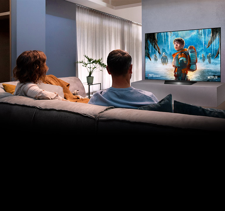 Para oglądająca na telewizorze w salonie romantyczny film
