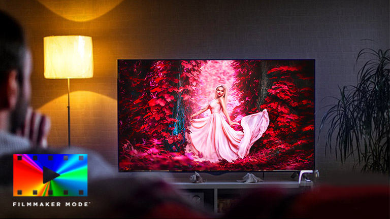 Mężczyzna siedzący na sofie w salonie z telewizorem, na ekranie którego odtwarzany jest kolorowy film