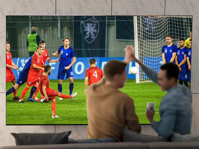 Ludzie oglądający sport w salonie na ultradużym ekranie telewizora