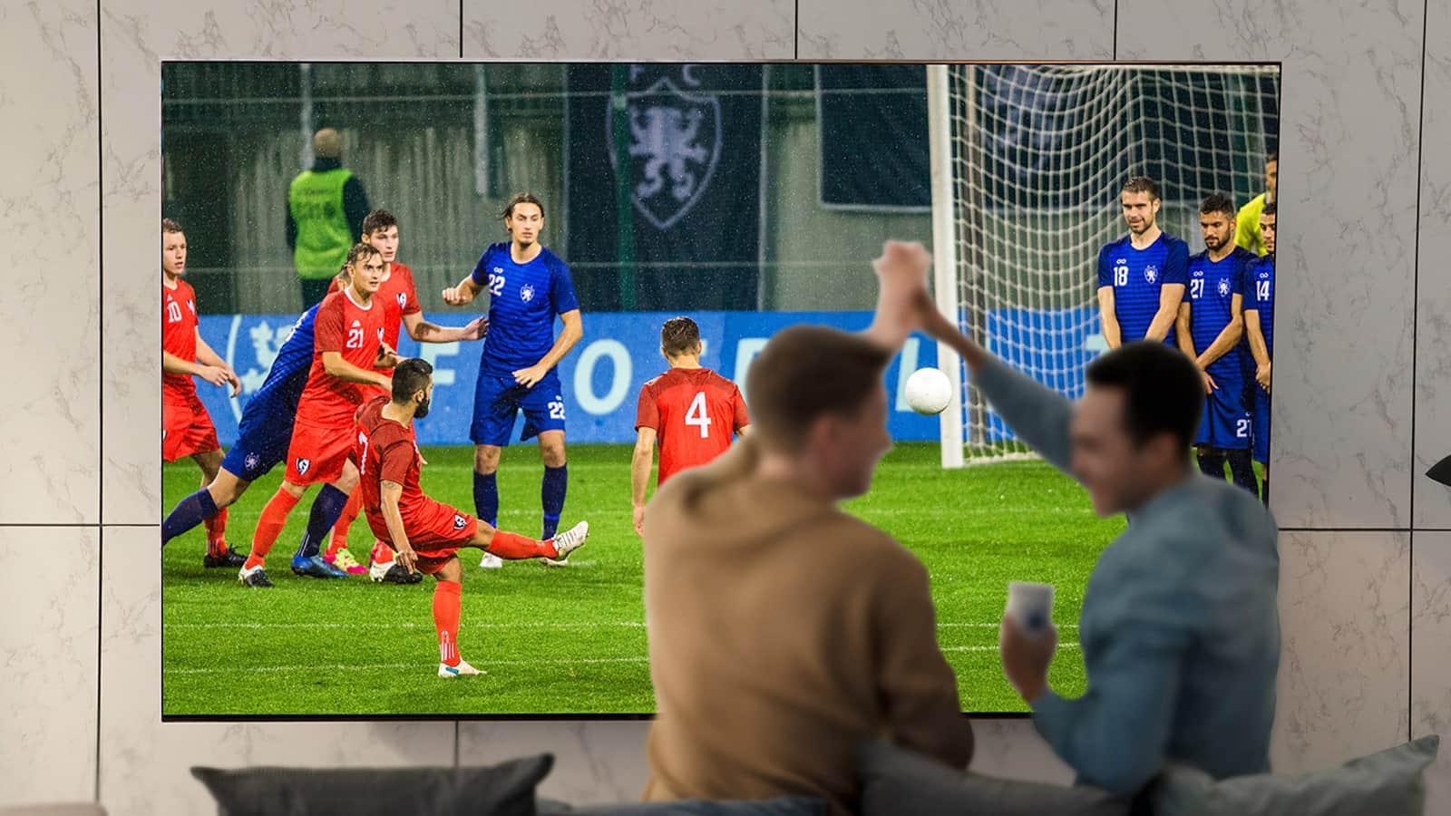 Ludzie oglądający sport w salonie na ultradużym ekranie telewizora