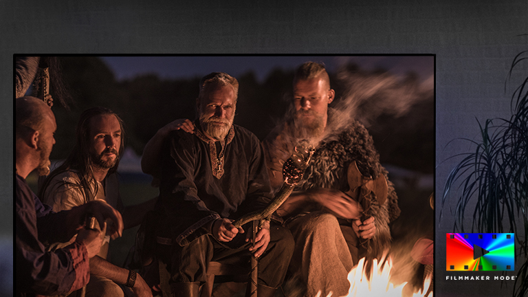 Mężczyzna siedzący na kanapie i oglądający film akcji. Dziewczyna na ekranie telewizora trzyma napięty łuk