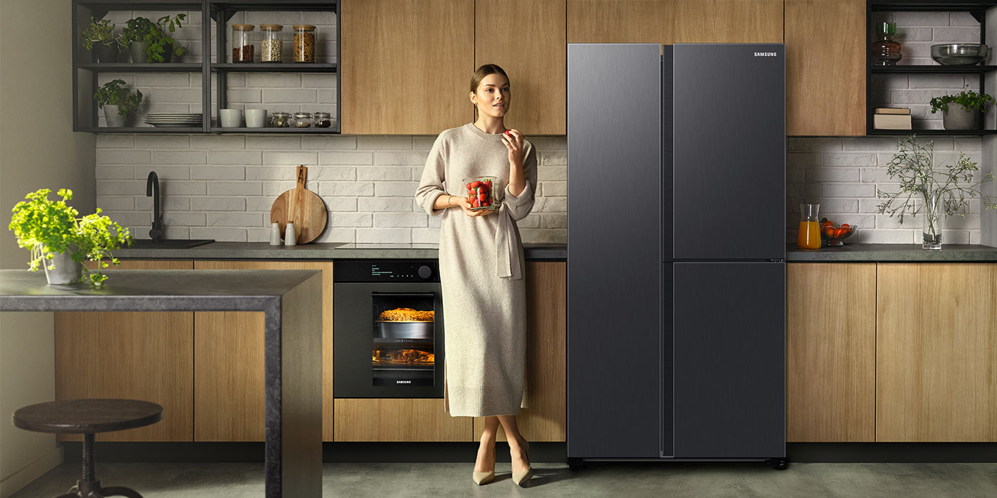 Minimalistyczna drewniana zabudowa kuchenna a w niej świetnie wkomponowana lodówka Samsung RH69B8931B1 w kolorze grafitowej stali – model do zamówienia na stronie Neonet