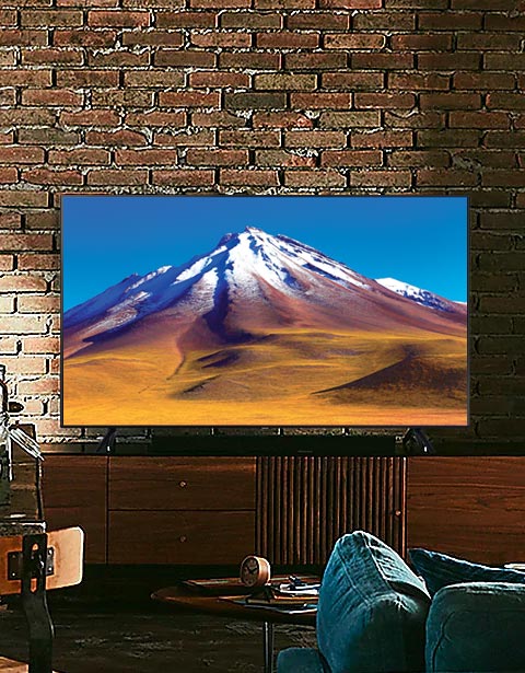 Telewizor Samsung stojący na półce z dawnym lat w kolorze ciemnego drewna w ciemnym pokoju