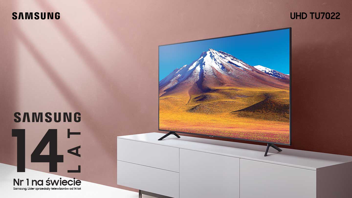Telewizor TU7022 na białej szafce RTV na tle łososiowej ściany