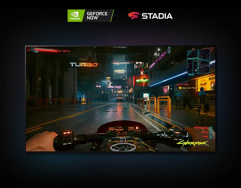 W scenie z gry Cyberpunk 2077 pokazanej na ekranie telewizora LG OLED gracz jedzie oświetloną neonami ulicą na motocyklu.