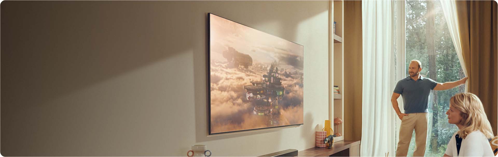 Duży telewizor znajduje się w jasnym salonie z roślinami i różnymi ozdobami.