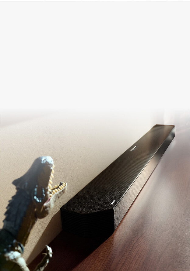 Czarny soundbar znajduje się na pólce w towarzystwie kolorowych wazonów i lamp.