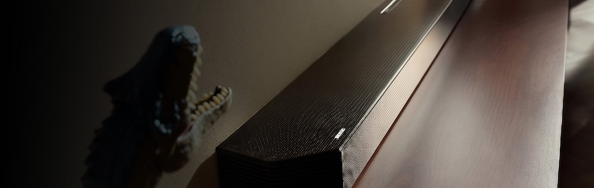 Czarny soundbar znajduje się na pólce w towarzystwie kolorowych wazonów i lamp.